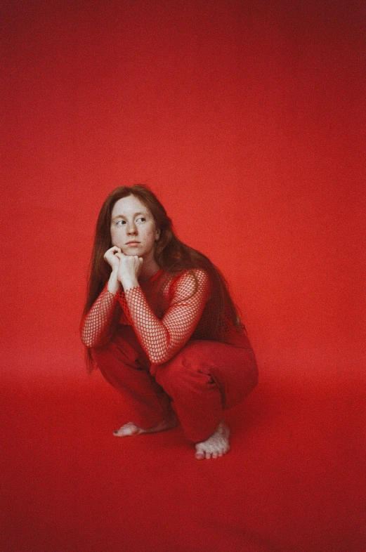 a woman sitting on top of a red floor, an album cover, by Anita Malfatti, tumblr, renaissance, wearing orange prison jumpsuit, long ginger hair, taken in 2022, dressed in red velvet