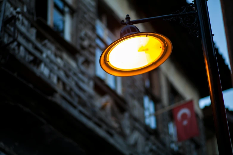 a close up of a street light with a building in the background, by Tobias Stimmer, hurufiyya, turkish and russian, cafe lighting, brown, yellow