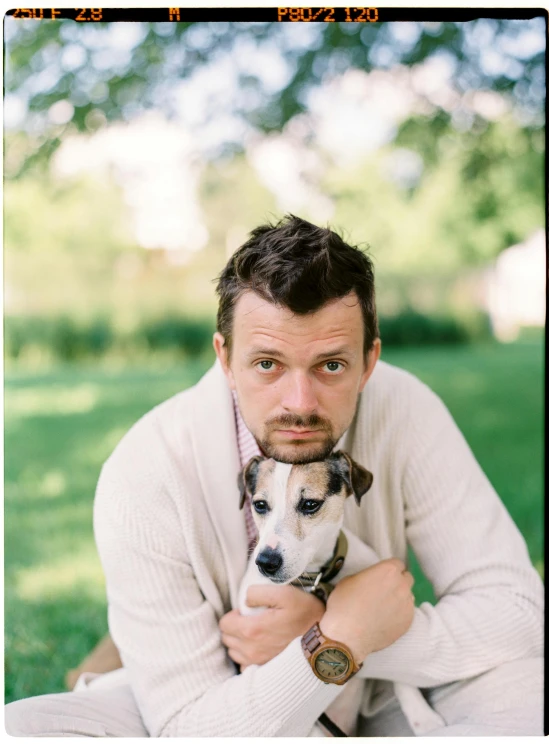 a man sitting in the grass holding a dog, inspired by Martin Schoeller, unsplash, portra, high quality photo, bjarke ingels, headshot profile picture