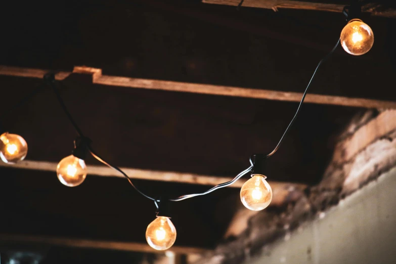 a string of light bulbs hanging from a ceiling, unsplash, light and space, inside a shed, worn, gothic lighting, two moons lighting