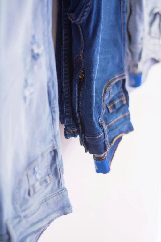 a pair of jeans hanging on a clothes rack, by Matija Jama, trending on unsplash, happening, wearing blue jacket, with a white background, close - up on detailed, mix of styles