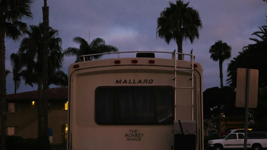 an rv parked in a parking lot with palm trees in the background, by James Morris, unsplash contest winner, renaissance, image of ronald mcdonald, nightfall, malibu canyon, photo taken from a boat