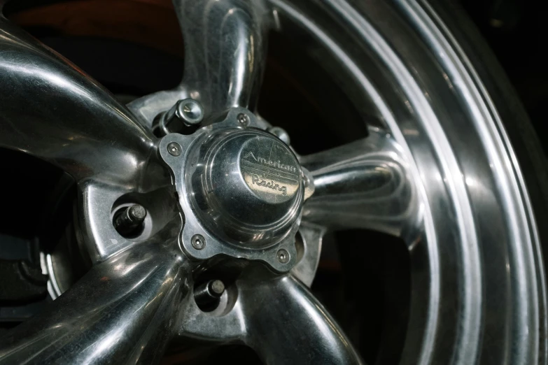 a close up of a wheel on a car, by Thomas Häfner, unsplash, photorealism, polished metal, restomod, americana, 1995