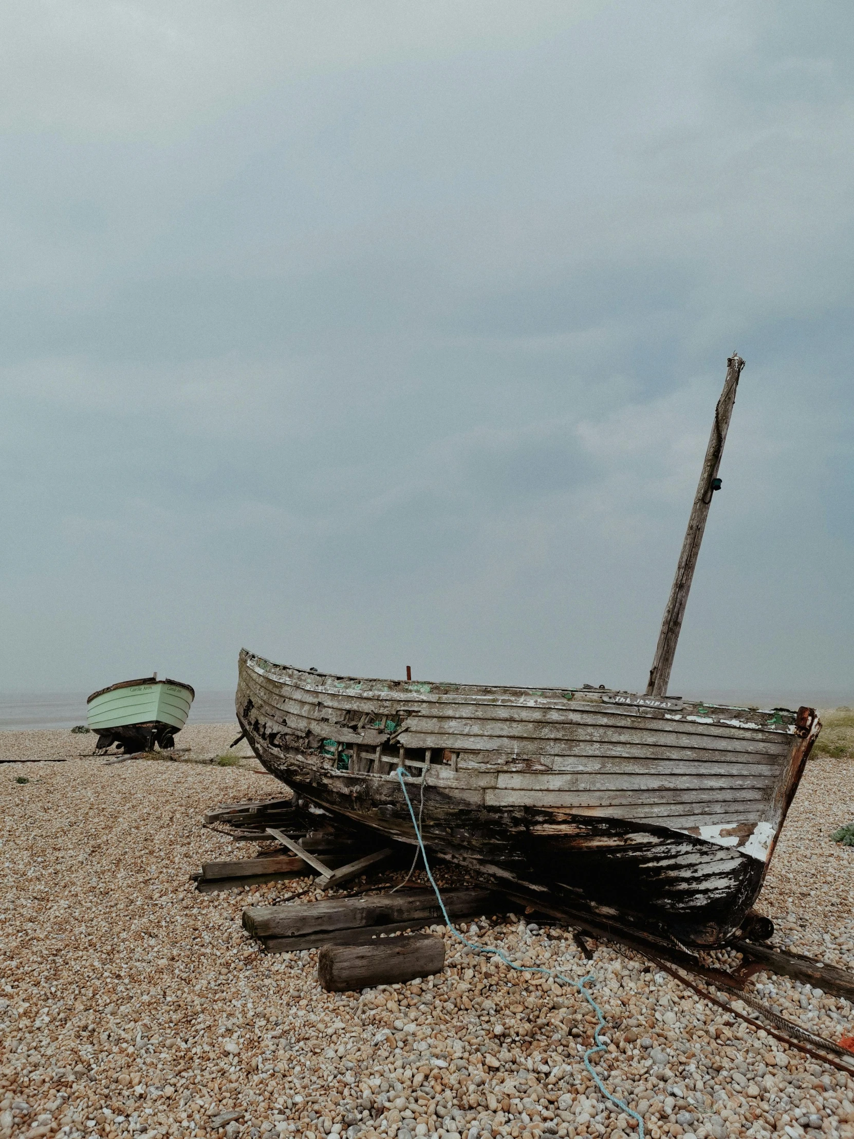 a boat sitting on top of a beach next to a wooden pole, inspired by Derek Jarman, unsplash, wrecked buildings, low quality photo, 4k -, van