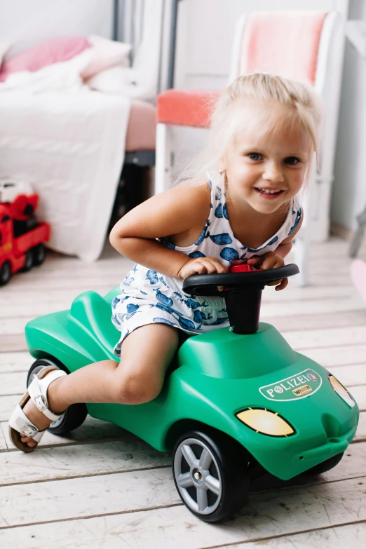 a little girl that is sitting on a toy car, jade green, zoomed in, small, brand