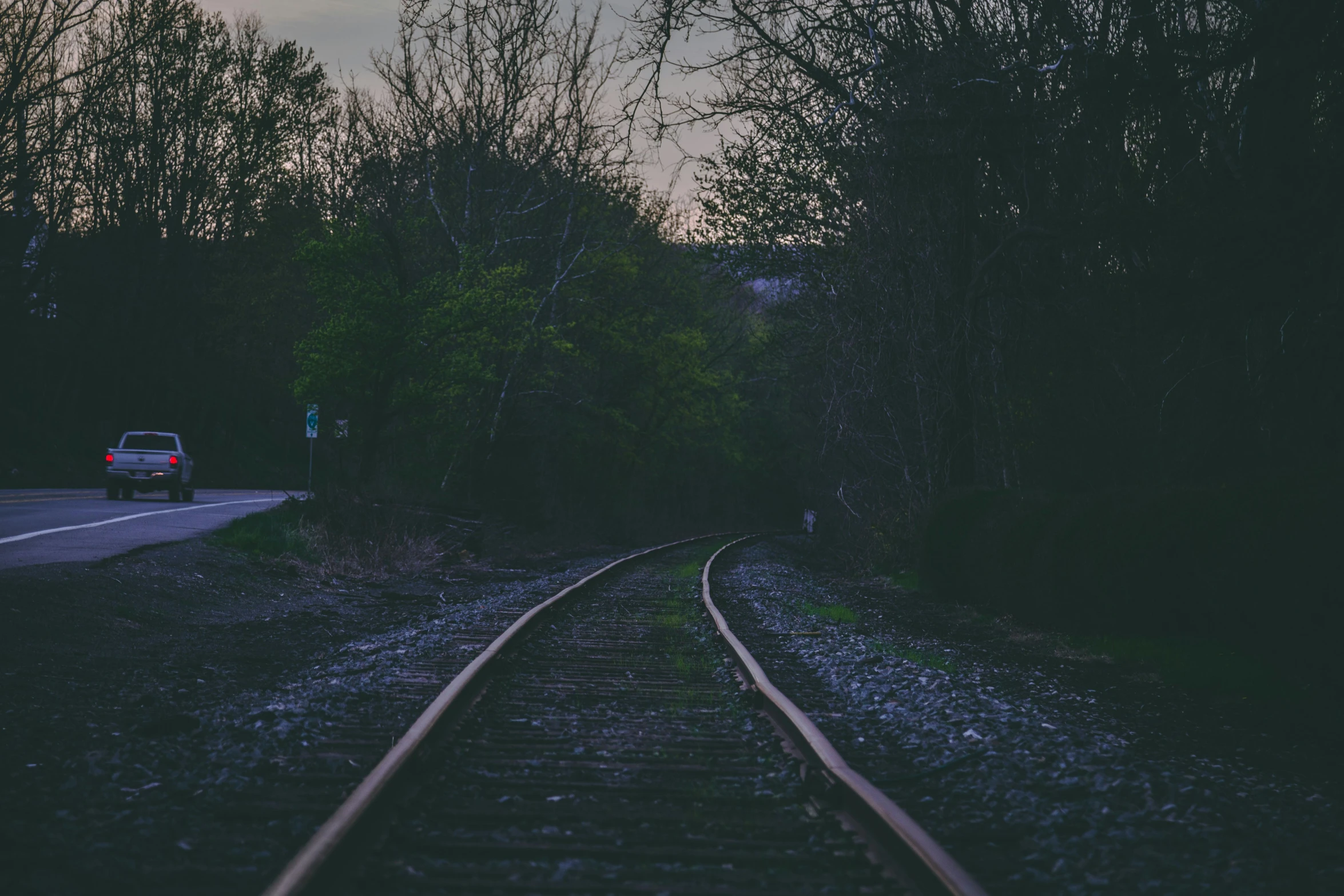 a car driving down a road next to a train track, an album cover, inspired by Elsa Bleda, unsplash, spooky photo, calm evening, spring evening, waiting