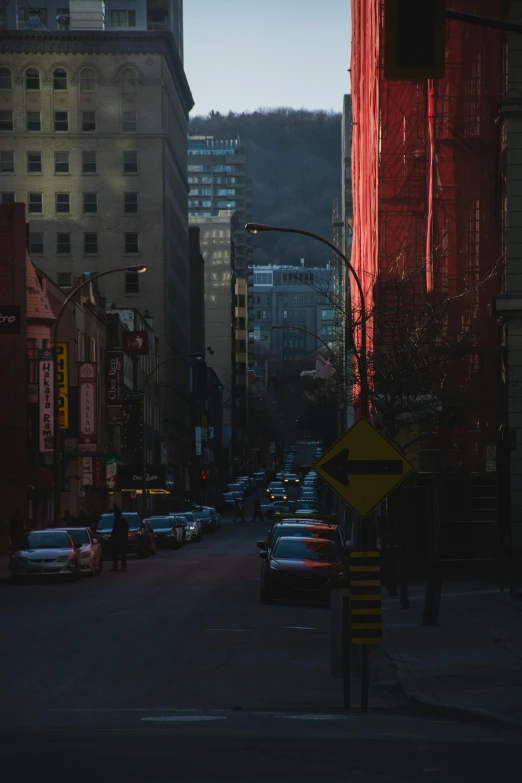 a street filled with lots of traffic next to tall buildings, a photo, inspired by Elsa Bleda, pexels contest winner, realism, vancouver, dramatic reddish light, deep shadows and colors, old city