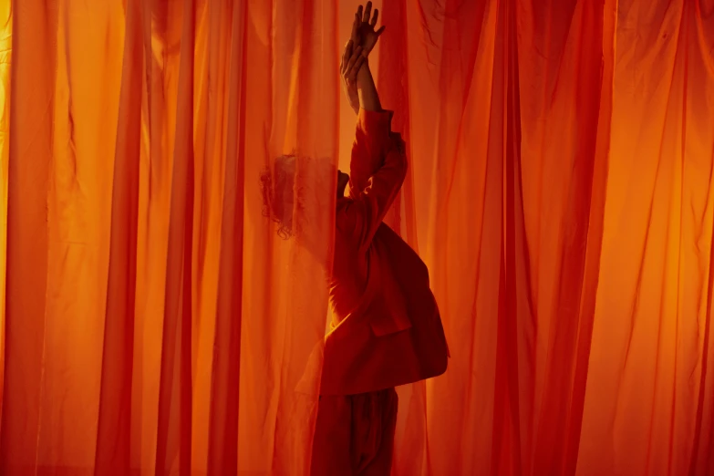 a woman standing in front of a red curtain, inspired by Georges de La Tour, pexels contest winner, orange spike aura in motion, sheer fabrics, showstudio, waving robe movement