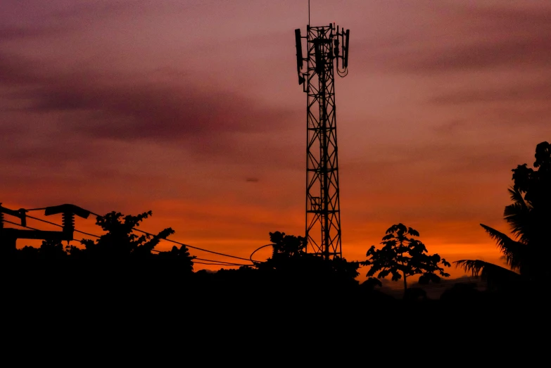 a tall tower sitting in the middle of a forest, by Alejandro Obregón, pexels, orange / pink sky, telephone wires, on black background, cell phone