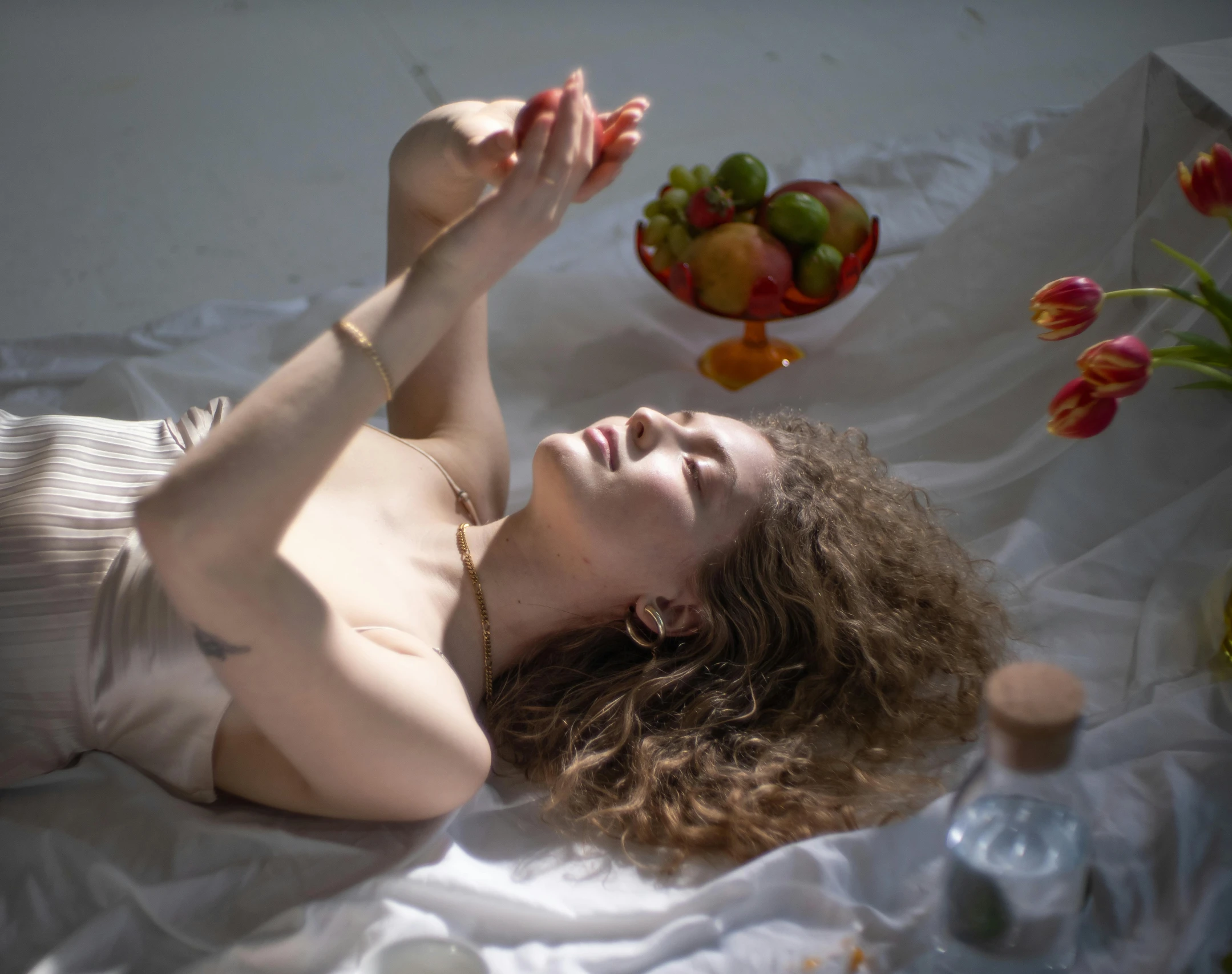 a woman laying on top of a bed next to a bowl of fruit, an album cover, inspired by Anna Füssli, pexels contest winner, renaissance, pale skin curly blond hair, emanating magic from her palms, sun puddle, a woman floats in midair