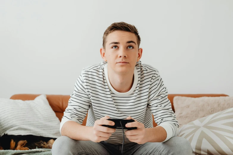 a man sitting on a couch holding a video game controller, by Julia Pishtar, trending on pexels, realism, looking serious, 1 6 years old, f 1 driver charles leclerc, discord profile picture