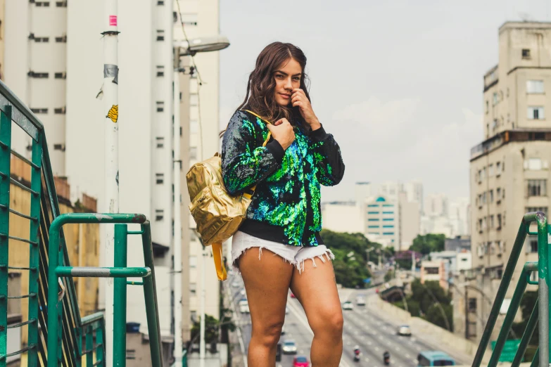 a woman walking down a set of stairs talking on a cell phone, an album cover, inspired by Elsa Bleda, pexels contest winner, happening, brazilan supermodel, sequin top, green colored bomber jacket, thick thighs