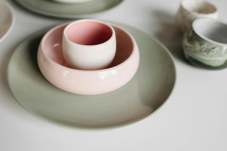 a close up of plates and bowls on a table, inspired by Giorgio Morandi, green and pink, 7 0 mm entrance pupil diameter, on a candle holder, pink