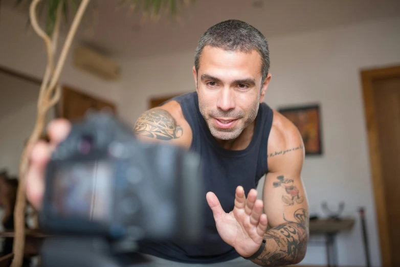 a close up of a person holding a camera, a tattoo, inspired by Nathan Oliveira, pexels contest winner, video art, athletic man in his 30s, home video, taking a selfie, actor