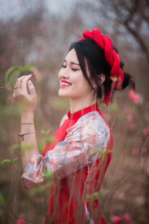 a woman in a red dress holding a flower, a picture, inspired by Cui Bai, pexels contest winner, aestheticism, smiling girl, traditional clothes, profile image, spring season