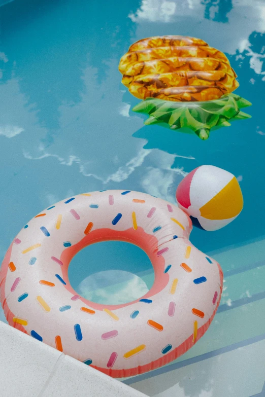 an inflatable donut floating in a pool, by Julia Pishtar, unsplash, pineapples, ice cream cone, toys, square