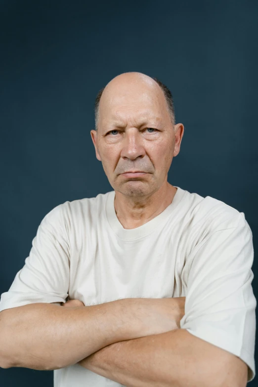 a man in a white shirt with his arms crossed, inspired by Martin Schoeller, unsplash, hyperrealism, grumpy [ old ], balding, annoyed, plain background