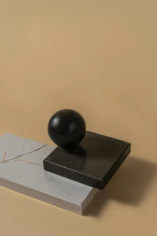 a black ball sitting on top of a marble block, an abstract sculpture, inspired by Isamu Noguchi, product image, small head, levitating, full product shot