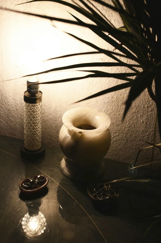 a candle sitting on top of a table next to a potted plant, a still life, water pipe, stippled lighting, spa, accent lighting : : peugot onyx