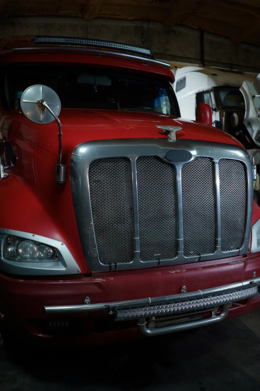 a red semi truck parked in a garage, a portrait, reddit, full frame image, custom headlights, ( mechanical ), cleaned up