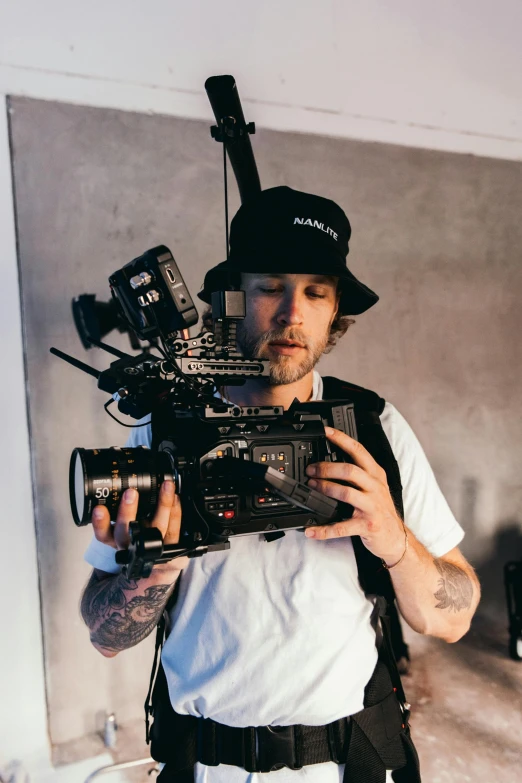 a man holding a camera in a room, production ig, tattooed, mrbeast, panavision panaflex x