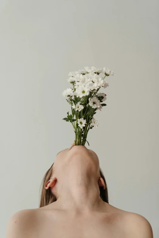 a woman with a bouquet of flowers on her head, trending on unsplash, aestheticism, fleshy creature above her mouth, but minimalist, upsidedown, white flower