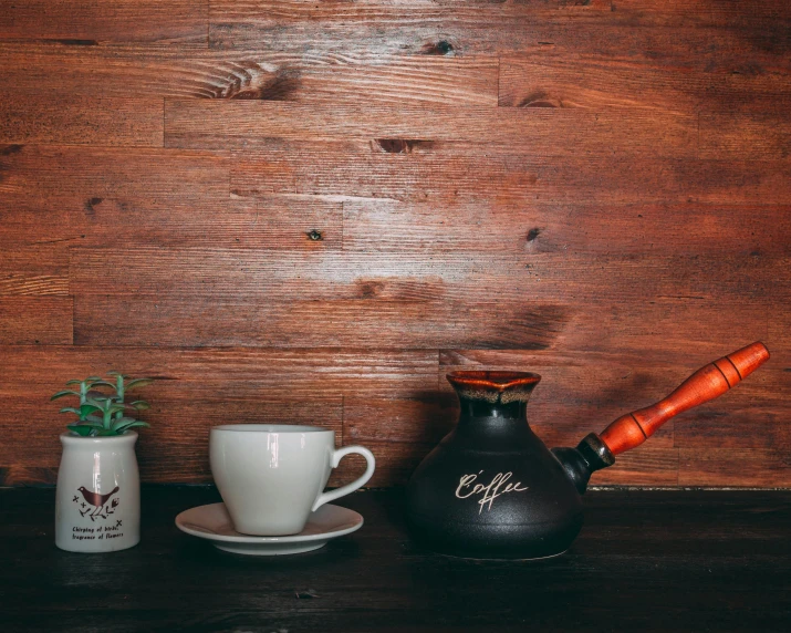 a coffee pot sitting on top of a table next to a cup, pexels contest winner, background image, wood accents, middle eastern, thumbnail