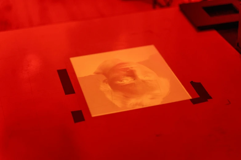 a red table with a picture of a dog on it, holography, her face is coated in a whitish, plotter, prototype, dim red light