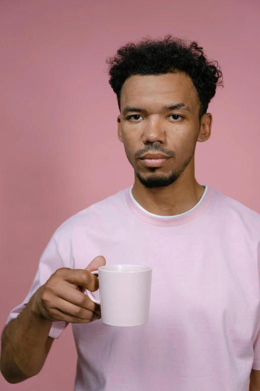 a man in a pink shirt holding a coffee cup, nonbinary model, mixed race, 2019 trending photo, blank stare