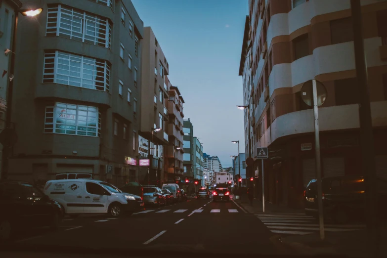 a street filled with lots of traffic next to tall buildings, by Alejandro Obregón, pexels contest winner, faded glow, square, spanish, moroccan city