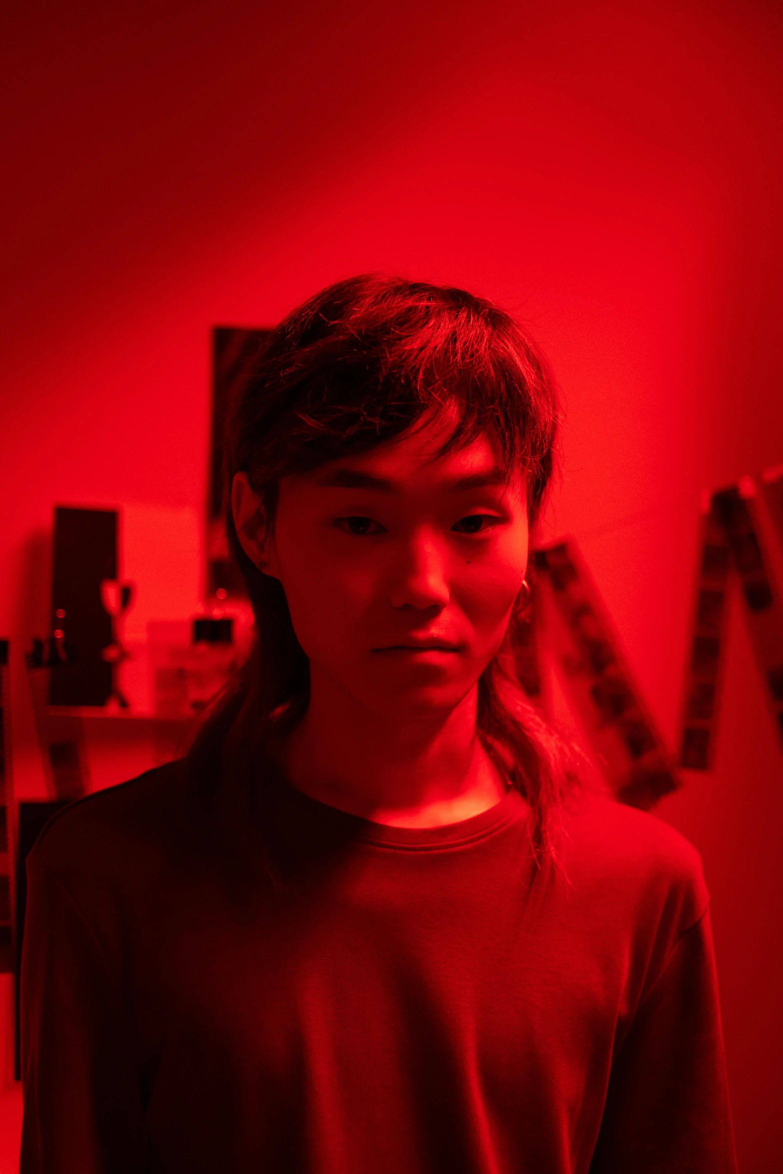 a person standing in a room with a red light, altermodern, androgynous face, asian features, indie film, ignant