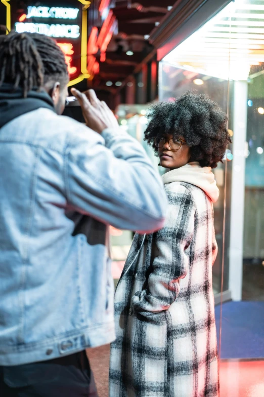 a man taking a picture of a woman in front of a store, pexels contest winner, long afro hair, cold lighting, meet the actor behind the scenes, promotional image