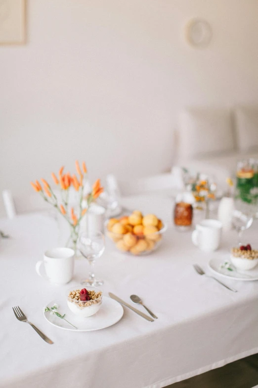 a white table topped with plates of food, a still life, unsplash, table set for second breakfast, in white room, manuka, white and orange