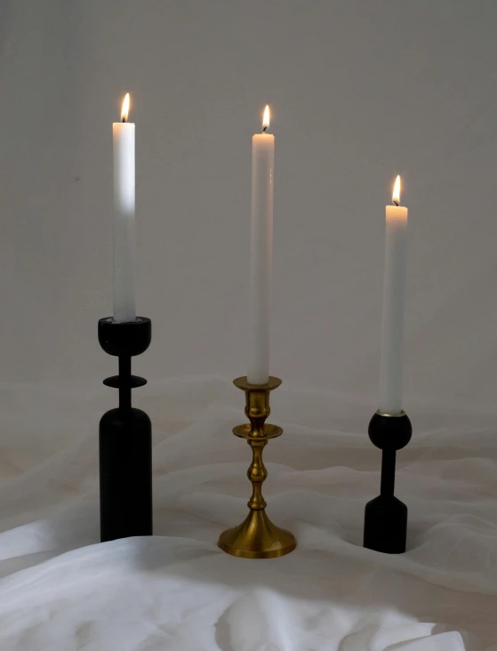 a group of three candles sitting next to each other, inspired by Diego Giacometti, baroque, one black, standing still, tall and small, made of wax and oil