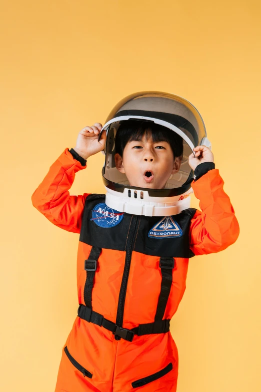 a little boy dressed in an orange space suit, pexels contest winner, all overly excited, visor over face, taejune kim, navy