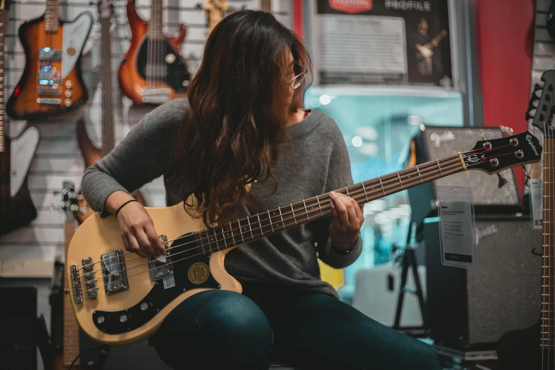 a woman playing a bass guitar in a music store, pexels contest winner, 💋 💄 👠 👗, half asian, lachlan bailey, profile image