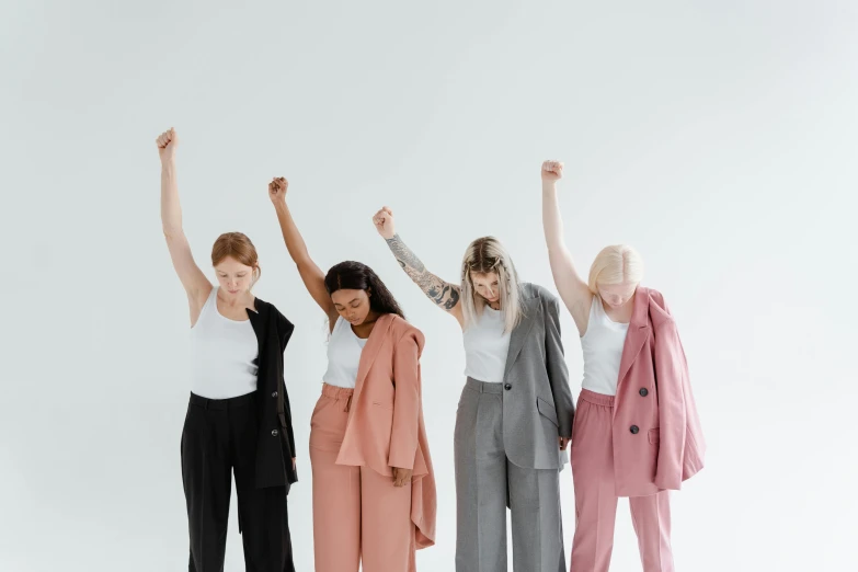 a group of women standing next to each other, trending on pexels, feminist art, triumphant pose, wearing a suit, with a white background, federation clothing