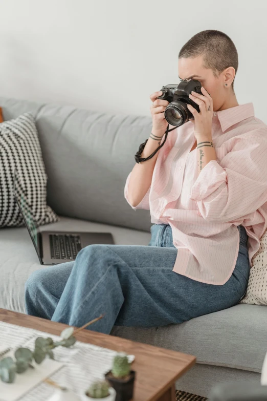 a woman sitting on a couch taking a picture with a camera, wearing a linen shirt, sitting at a computer, outfit photograph, outfit photo