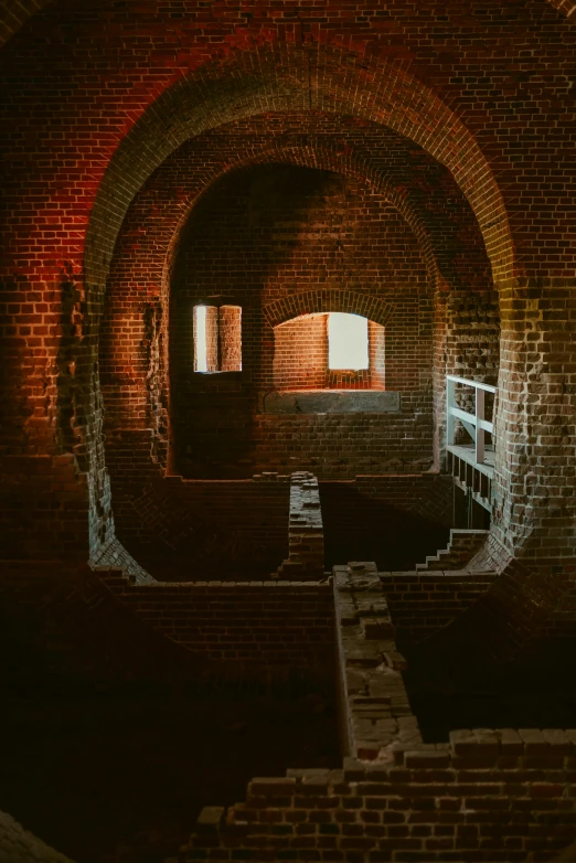 a tunnel in the middle of a brick building, a colorized photo, by James Bard, pexels contest winner, renaissance, dark hazy room, cannons, rows of windows lit internally, afternoon sunlight