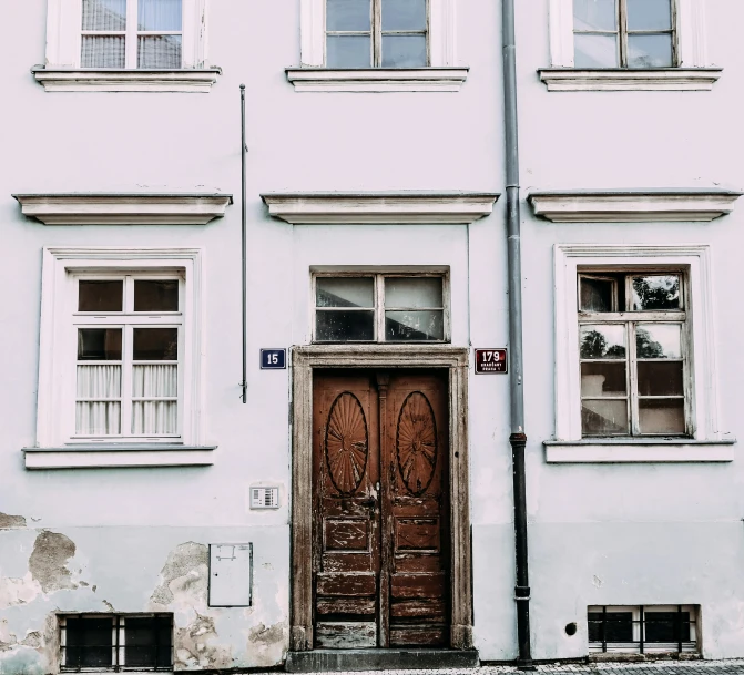 a red fire hydrant sitting in front of a building, by Kristian Zahrtmann, pexels contest winner, wood door, old apartment, white houses, high details photo