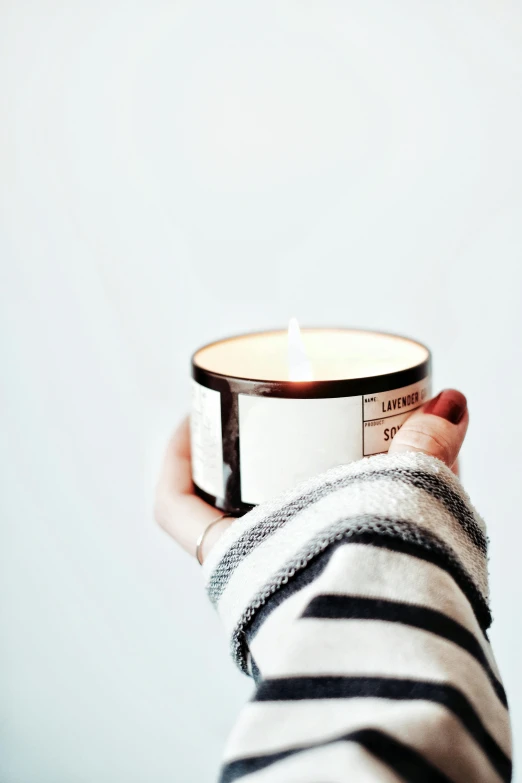 a person holding a candle in their hand, shiny silver, lumi, coffee smell, filled with natural light