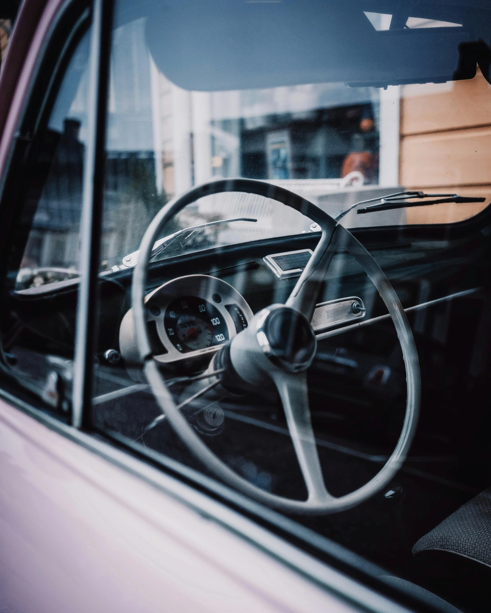 a close up of a steering wheel on a car, by Carey Morris, pexels contest winner, hypermodernism, looking in the window, silver and muted colors, 1960s style, microbus