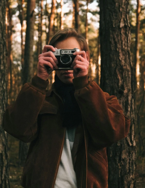 a man taking a picture with a camera in the woods, inspired by Elsa Bleda, unsplash contest winner, non binary model, lovingly looking at camera, vintage aesthetic, ansel ]
