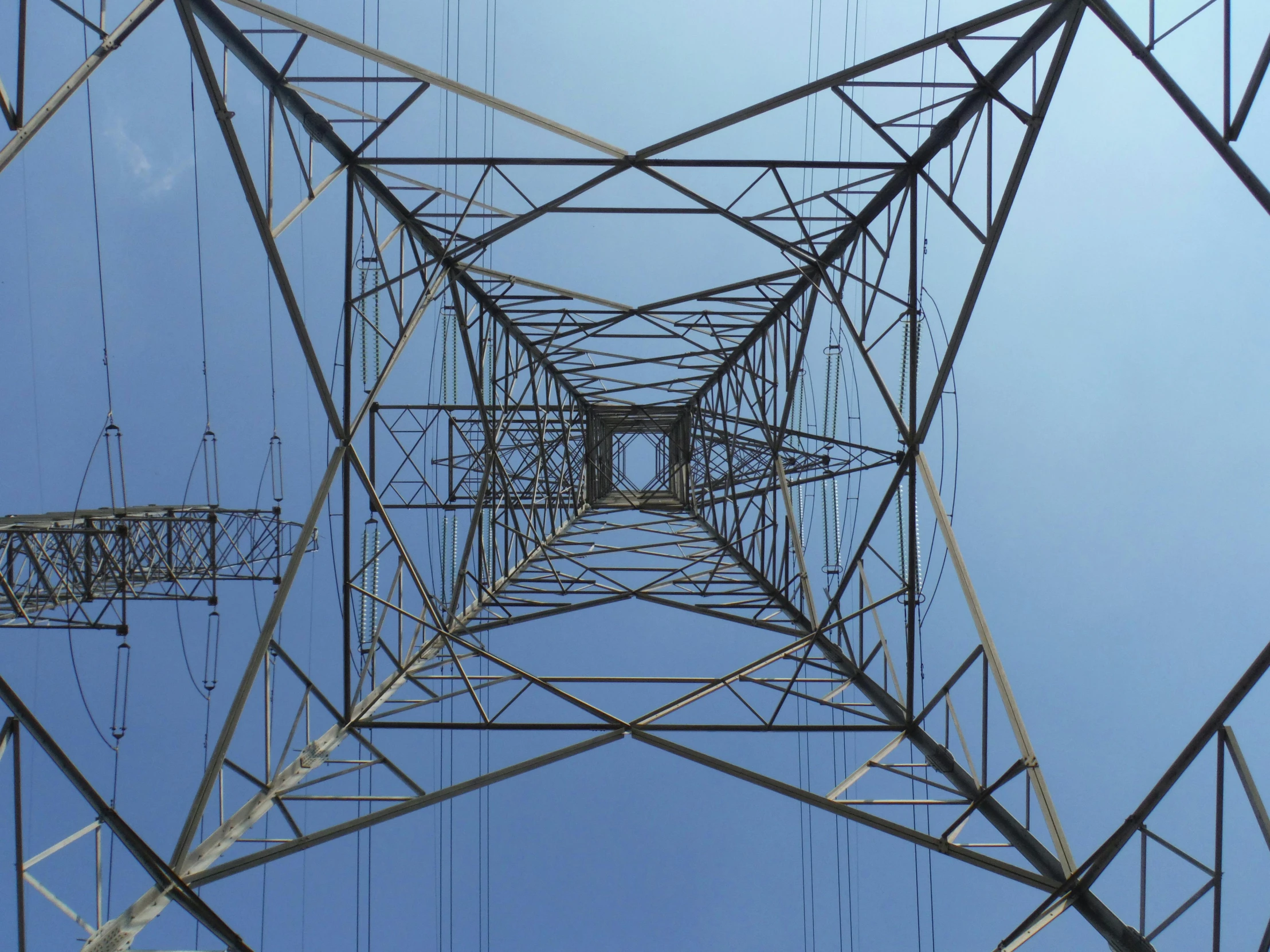 a high voltage tower with a blue sky in the background, by Carey Morris, pexels contest winner, renaissance, highly detailed symmetry, halogen, looking from slightly below, extremely clear and coherent