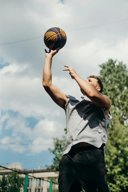 a man standing on top of a basketball court holding a basketball, unsplash, wearing a tank top and shorts, mid action swing, nature outside, pictured from the shoulders up