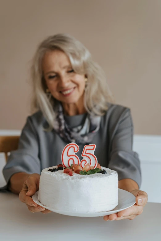 a woman sitting at a table with a cake in front of her, pexels contest winner, he is about 6 0 years old, 2 5 6 x 2 5 6 pixels, triple six, white haired lady