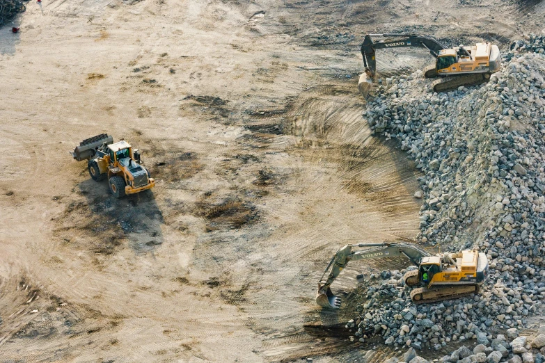a group of construction equipment sitting on top of a dirt field, unsplash, figuration libre, aerial footage, dry river bed, profile image, landslides
