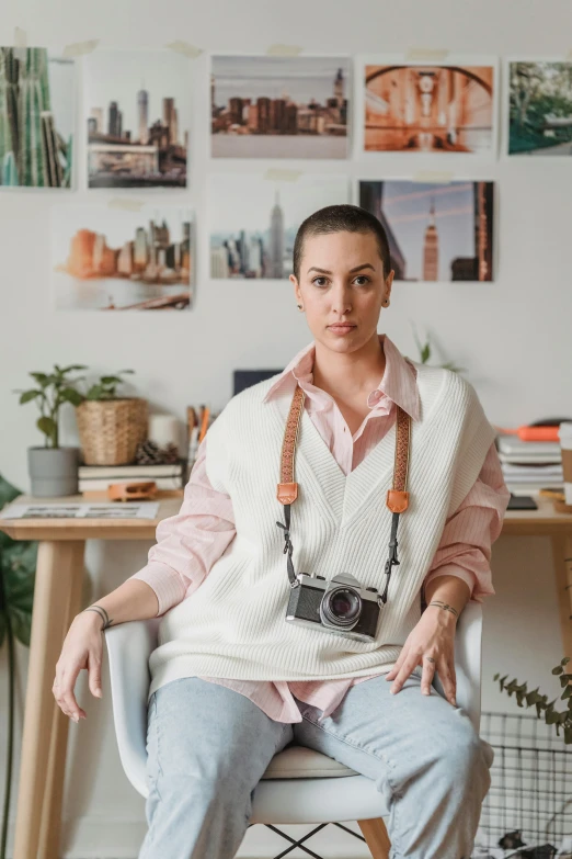 a woman sitting in a chair holding a camera, dasha taran, on a desk, wearing a designer top, portrait n - 9