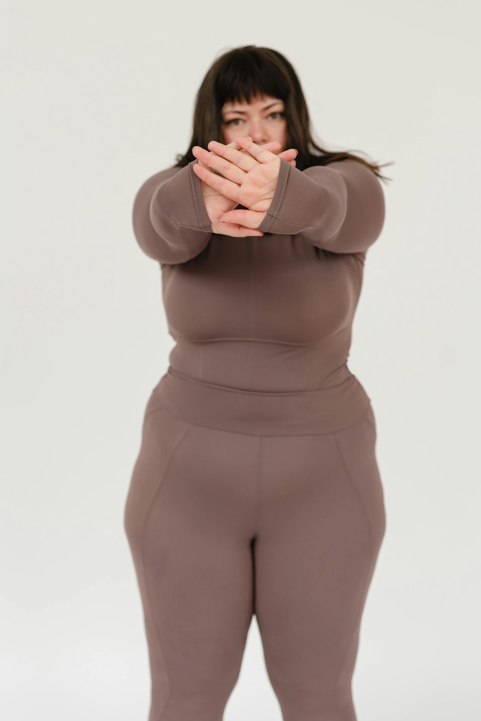 a woman covering her face with her hands, muted colored bodysuit, wearing a track suit, full figured, fully chocolate