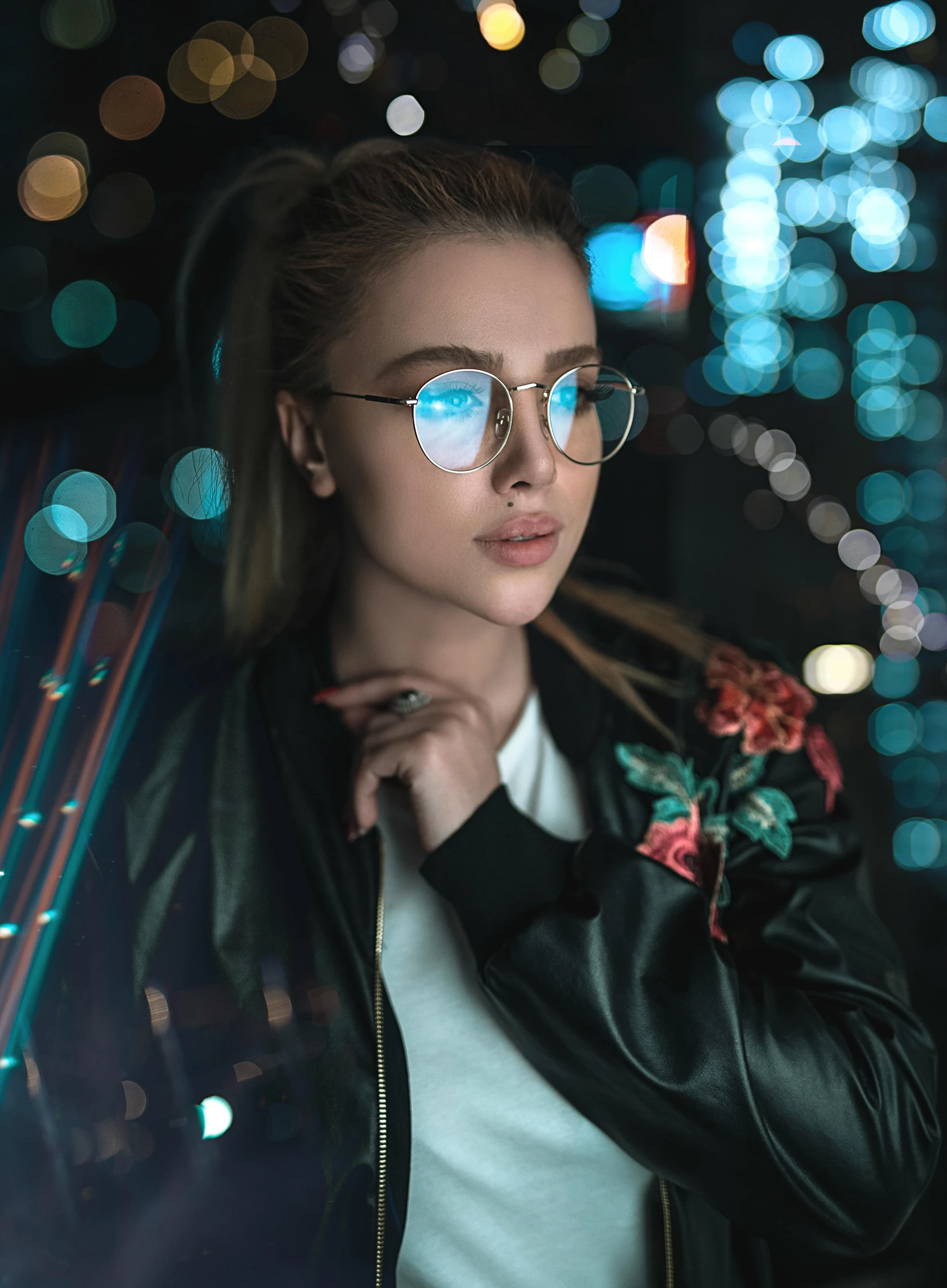 a woman wearing glasses standing in front of a city at night, a picture, inspired by Elsa Bleda, trending on pexels, holography, square rimmed glasses, glowwave girl portrait, wlop and ross tran, portrait mode photo